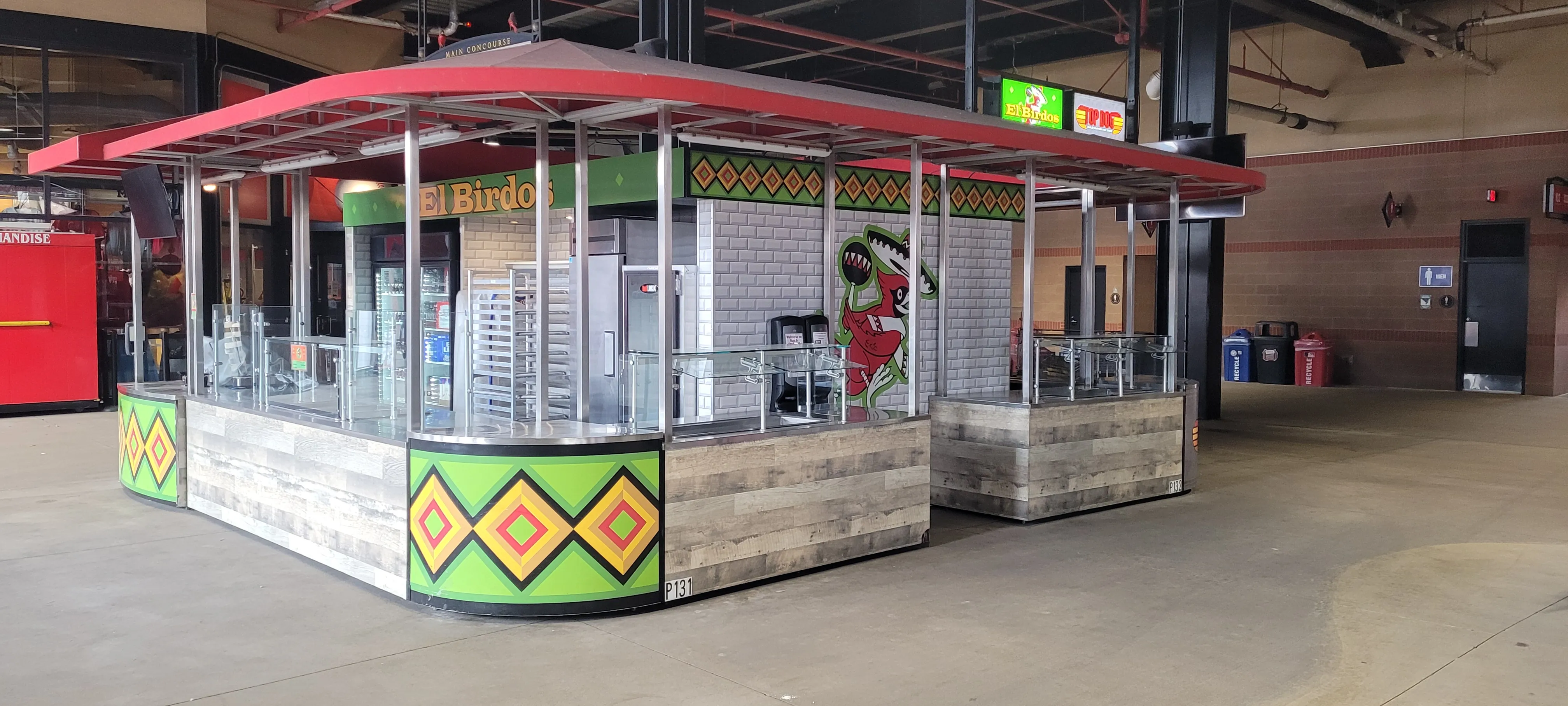 El Birdos concourse kiosk with a red canopy and green diamond pattern panels