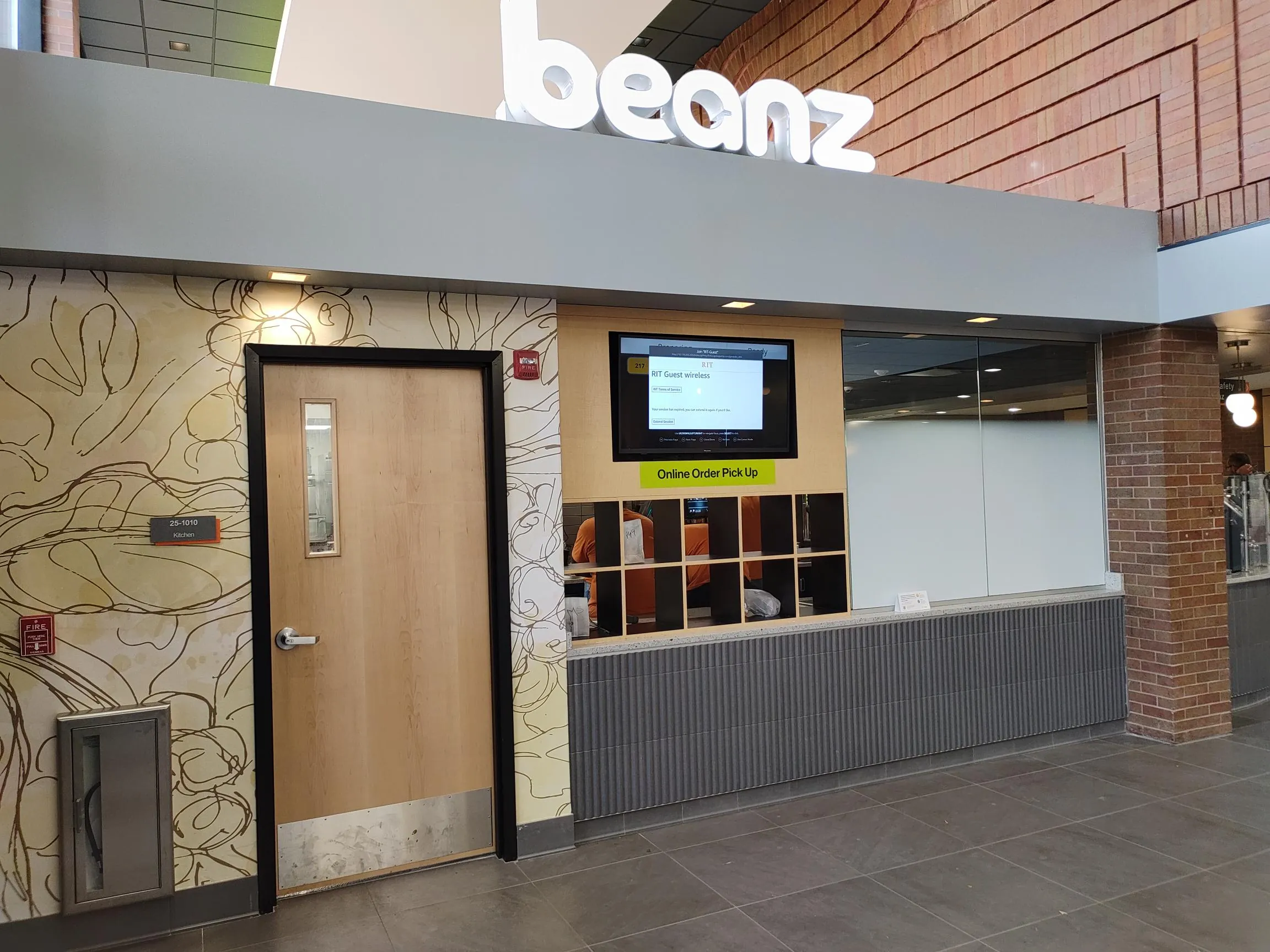 Beanz sign above the online order pickup window with cubbies, next to a kitchen door